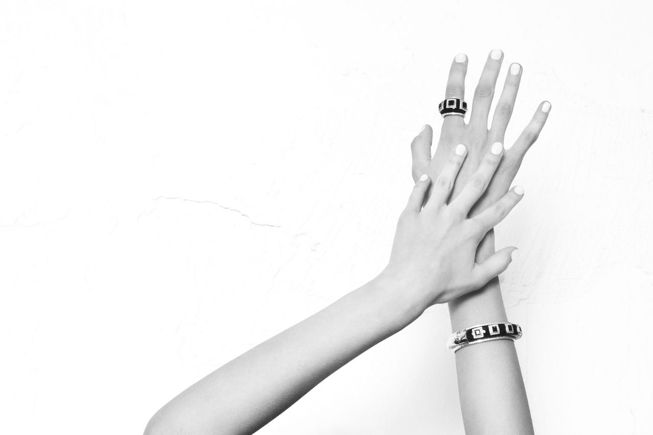 Mastering the First Impression: Your intriguing post title goes here Black and white photo showcasing elegant hands adorned with rings and bracelets on a white background.