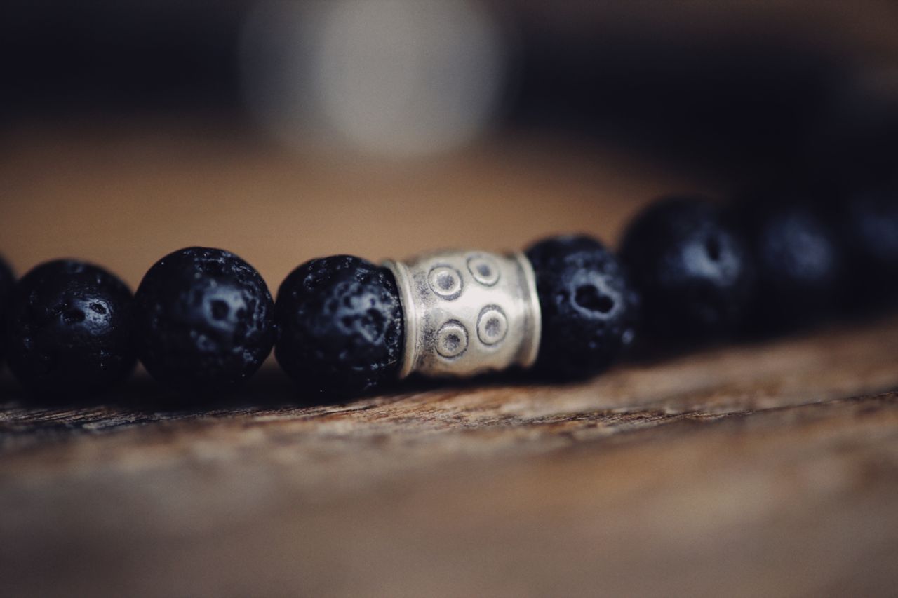 The Art of Drawing Readers In: Your attractive post title goes here Detailed close-up of a beaded bracelet with dark textured beads and a decorative metal accent piece.